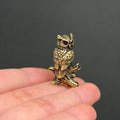 Miniature brass owl figurine on branch