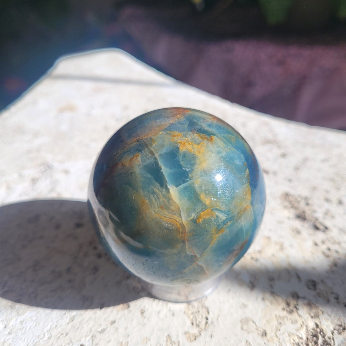 Natural Blue Onyx sphere showing blue calcite with warm golden and rust mineral patterning
