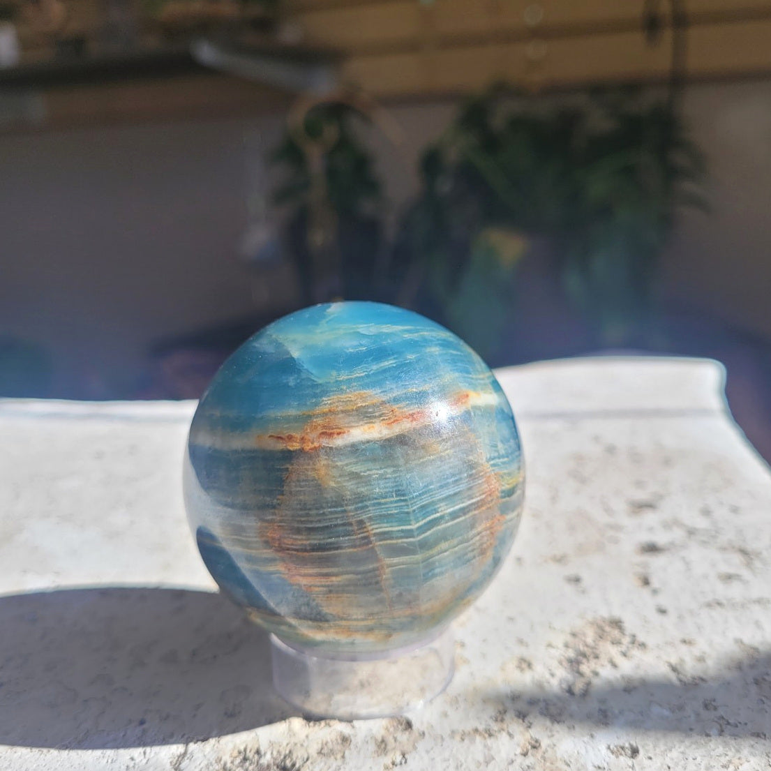 56.7mm Blue Onyx sphere in sunlight showing blue, cream and rust-gold banding