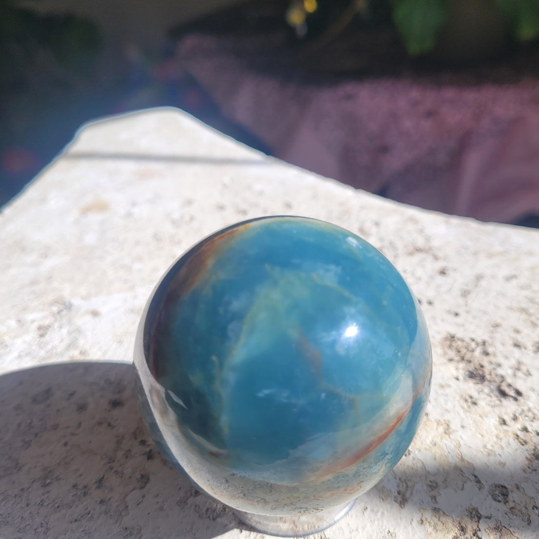56.7mm Blue Onyx sphere in sunlight showing translucent blue calcite and natural color variation
