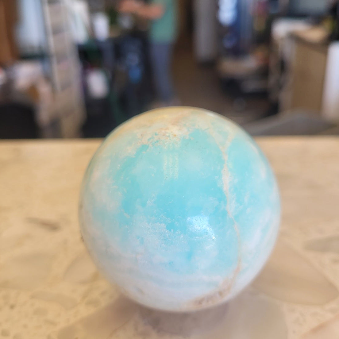 62mm Caribbean Calcite sphere in ambient indoor light showing soft aqua and cream color