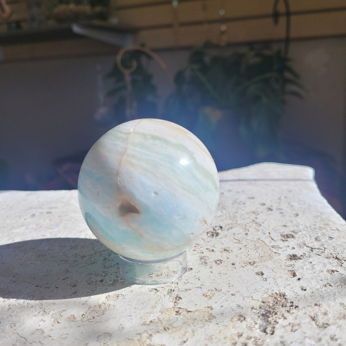 Natural Caribbean Calcite sphere showing seafoam banding and a small mineral cavity