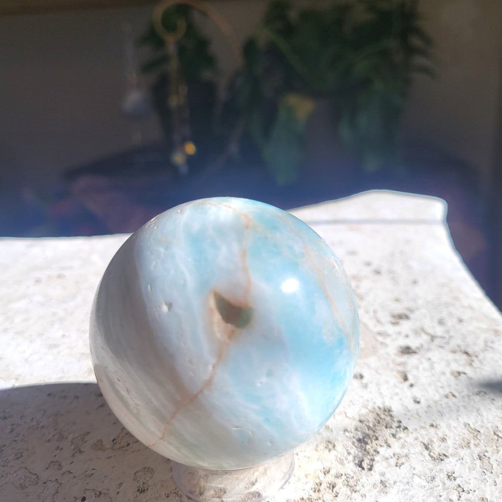 Caribbean Calcite sphere showing aqua blue and creamy white mineral patterning in sunlight