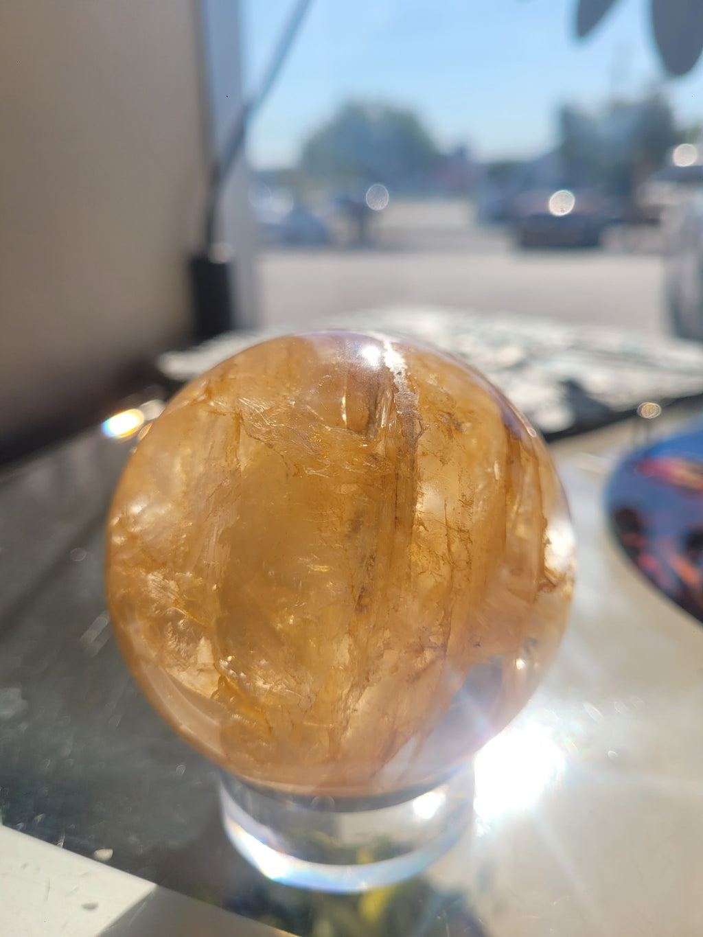 69.3mm Golden Healer Quartz sphere in sunlight showing a large translucent crystalline plane and golden inclusions