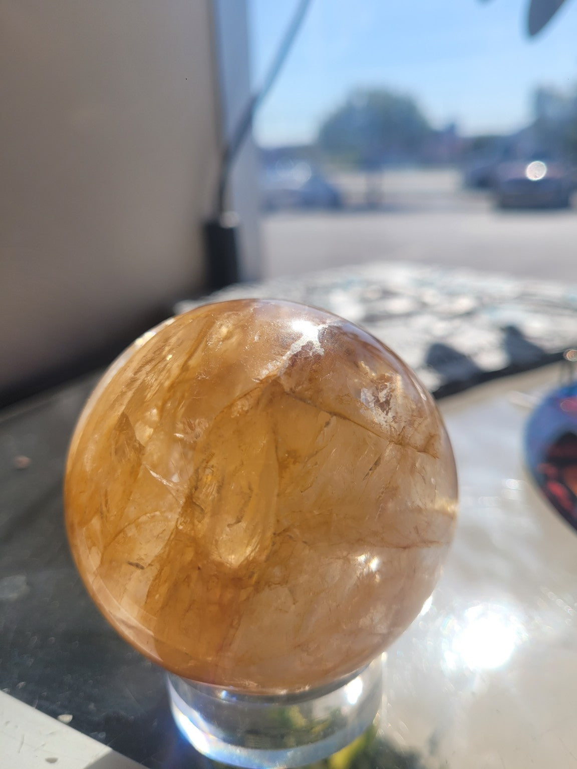 Natural Golden Healer Quartz sphere in sunlight showing translucency, golden veils and internal structure
