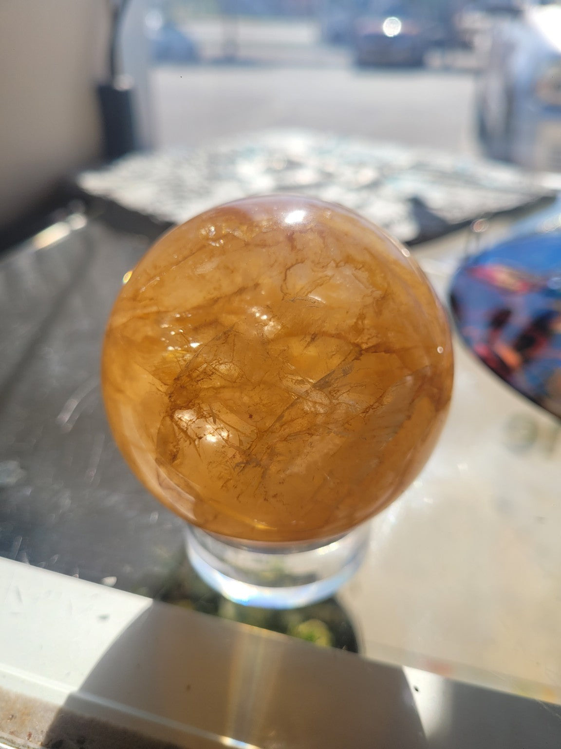 Golden Healer Quartz sphere showing darker iron-colored veining and natural internal landscape